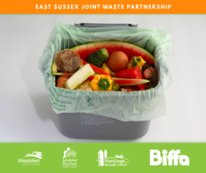 A kitchen caddy filled with food waste such as watermelon rind, eggshells, vegetables, and tea bags. The caddy sits on a white background with the East Sussex Joint Waste Partnership and council logos displayed.